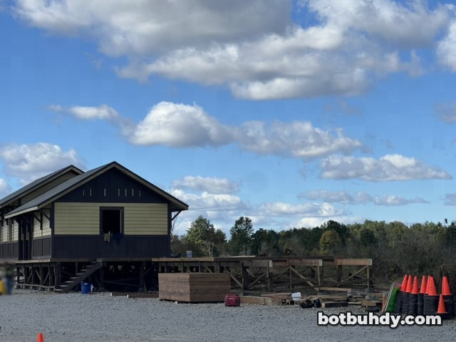 The yellow station set seen from the side, with a lumber pile and stacked orange cones in front.