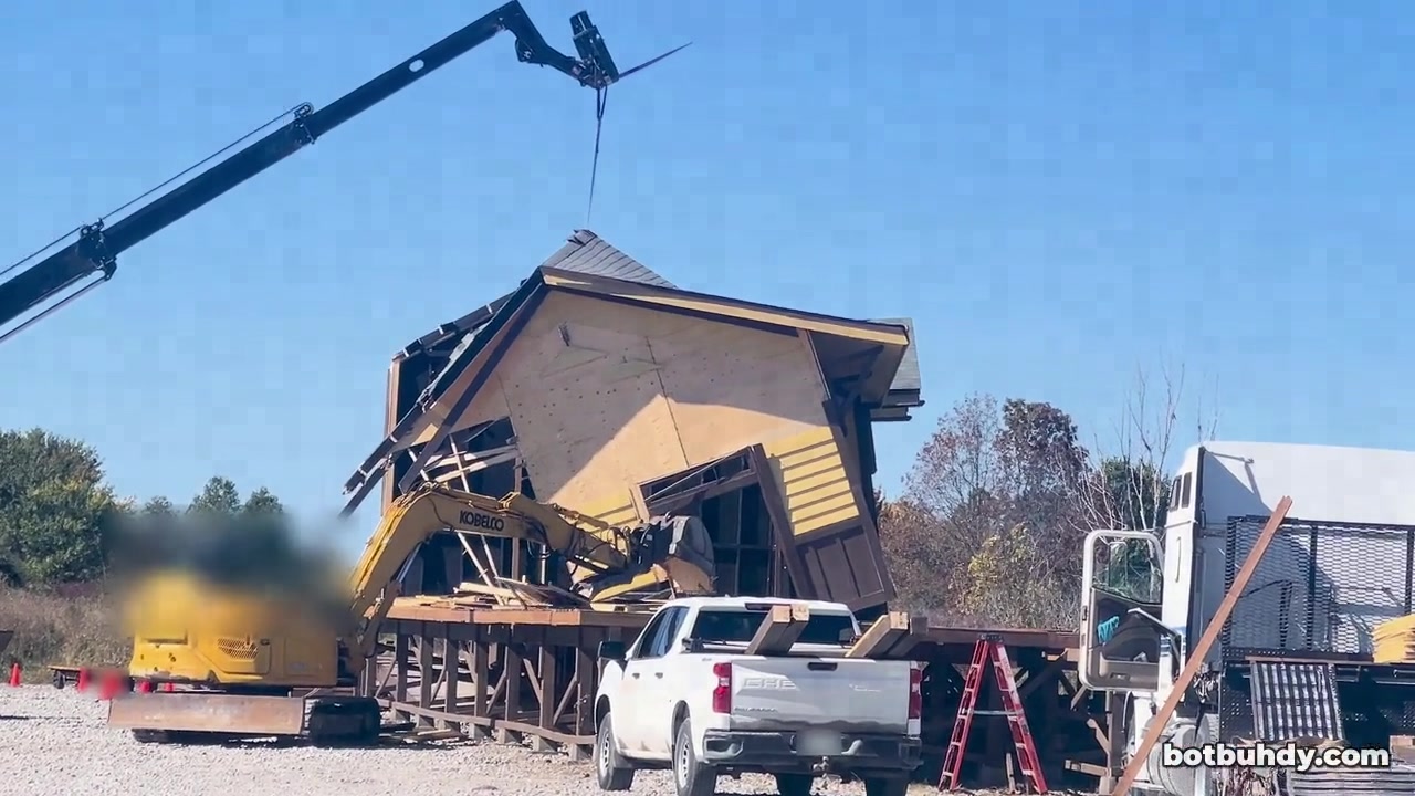 An excavator pulling at the station wall until the building collapses into a heap.