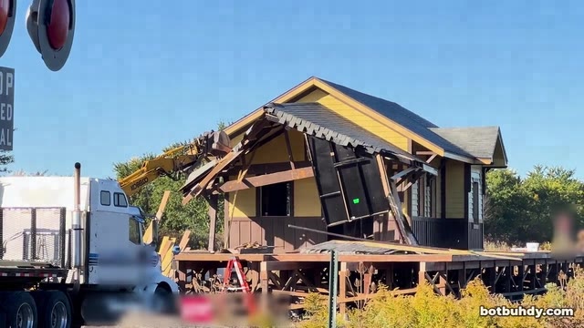 An excavator claw tearing at the station porch roof until it collapses.