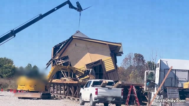 An excavator pulling at the station wall until the building collapses into a heap.