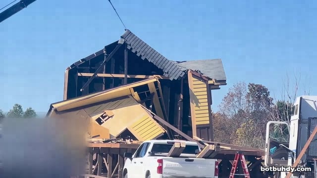 The wrecked station with one gable still standing and an excavator claw above it.
