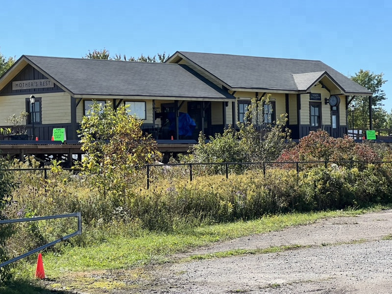 The station set in bright daylight under a blue sky, with gear under blue tarps on the deck and an orange cone by the path.