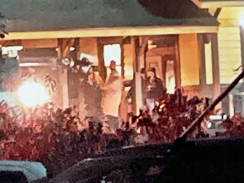 Enlarged close view of crew members and a bright work light on the lit porch at night.
