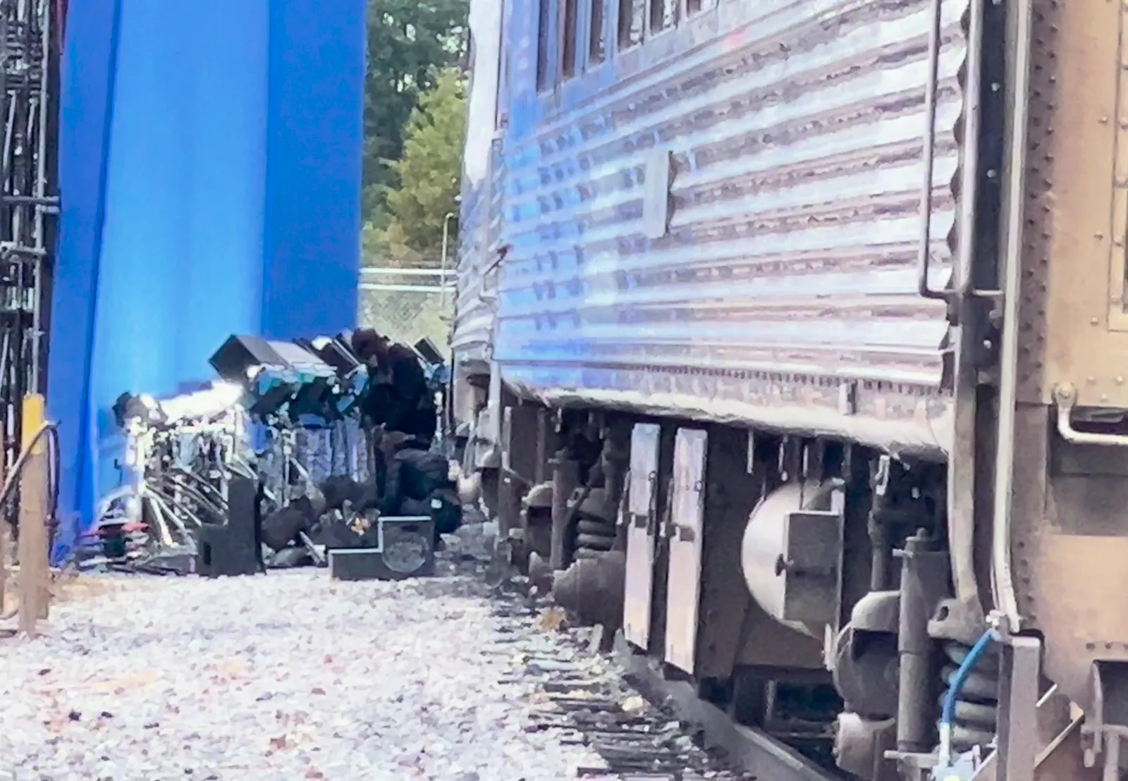 A row of film lights on stands between the blue screen and the side of the train car