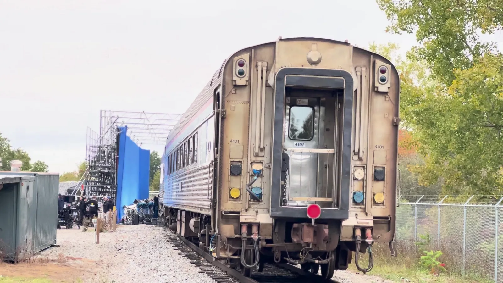 Wide view of the end of the passenger car on its track, with the blue screen and scaffold tower beside it